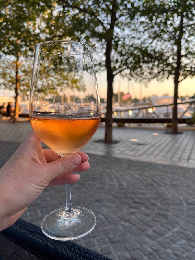 a glass of rose with a view of the wharf sunset in dc
