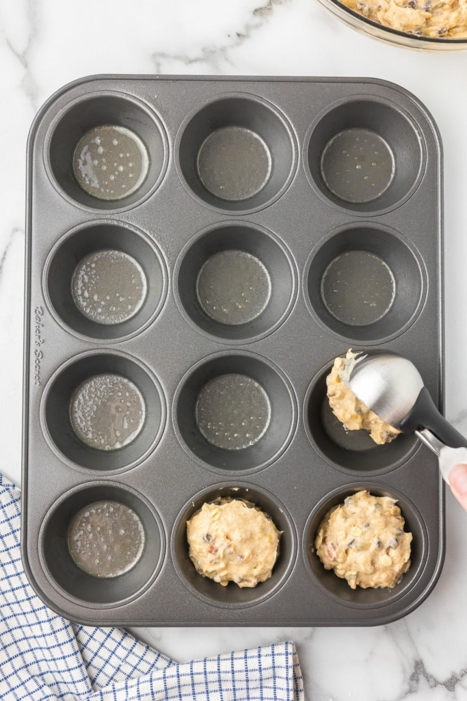 batter being scooped into a muffin tin