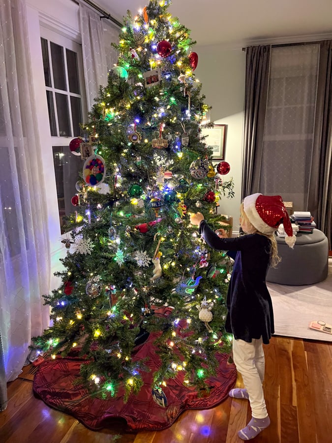girl with santa hat decorating christmas tree