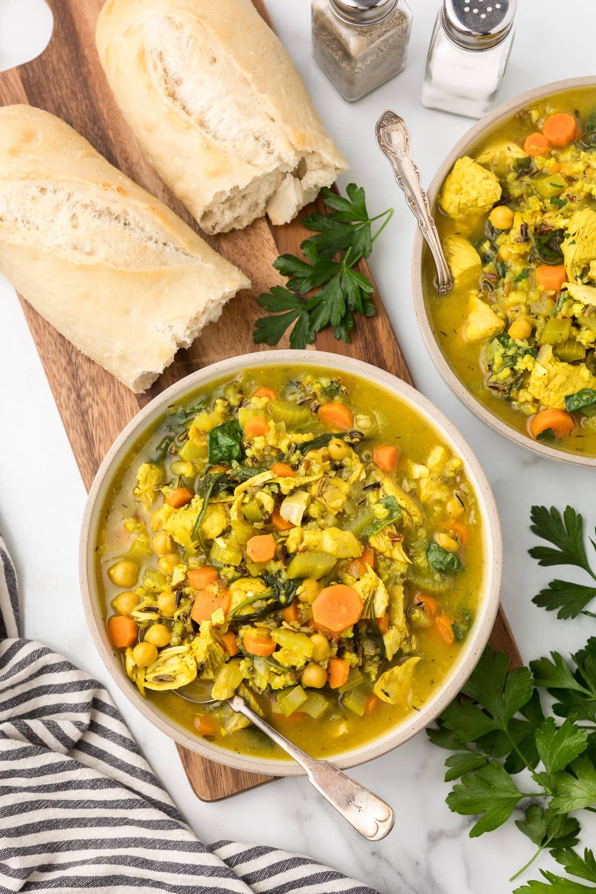 shredded turkey soup with wild rice and vegetables in a bowl next to a baguette