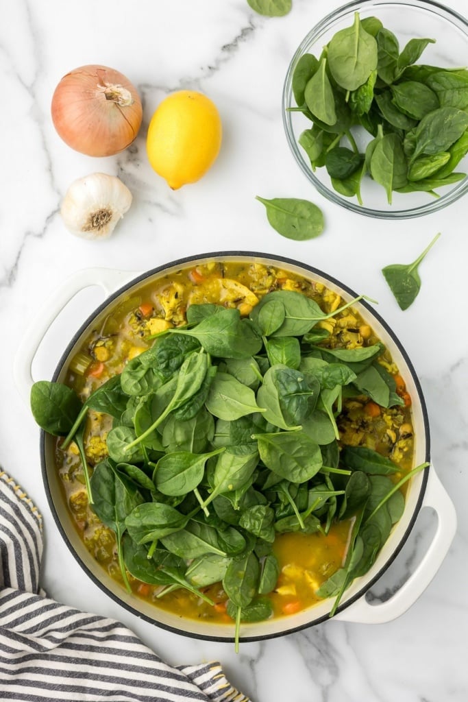 spinach in a large ceramic pot with broth