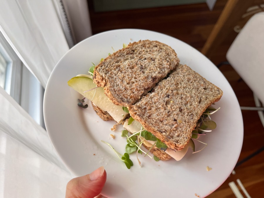 hummus, pickle, and turkey sandwich on a white plate.