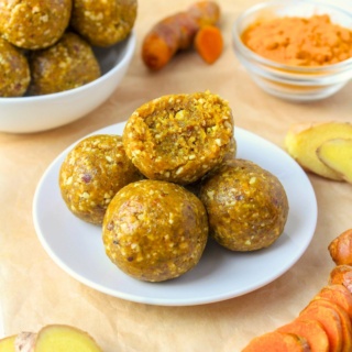 ginger energy bites on a plate with sliced turmeric root