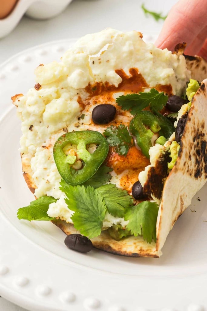 feta fried eggs with black beans and jalapeno slices on a tortilla