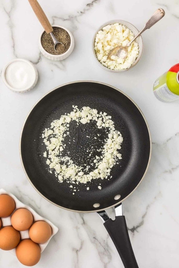 feta cheese sprinkled in a circle on a skillet