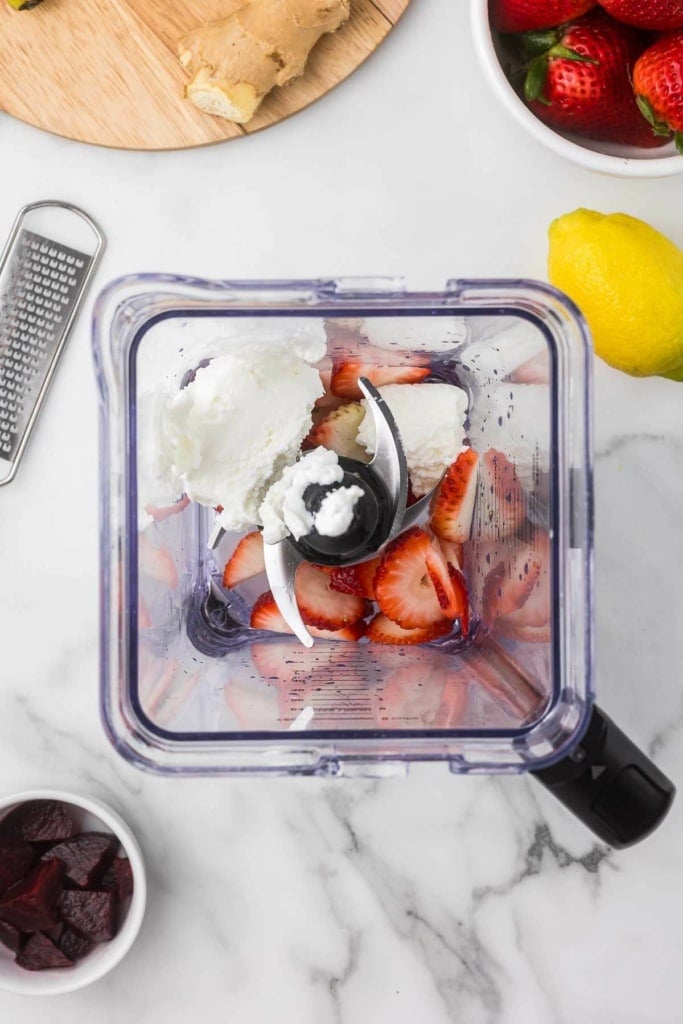 a blender with chopped strawberries and Greek yogurt